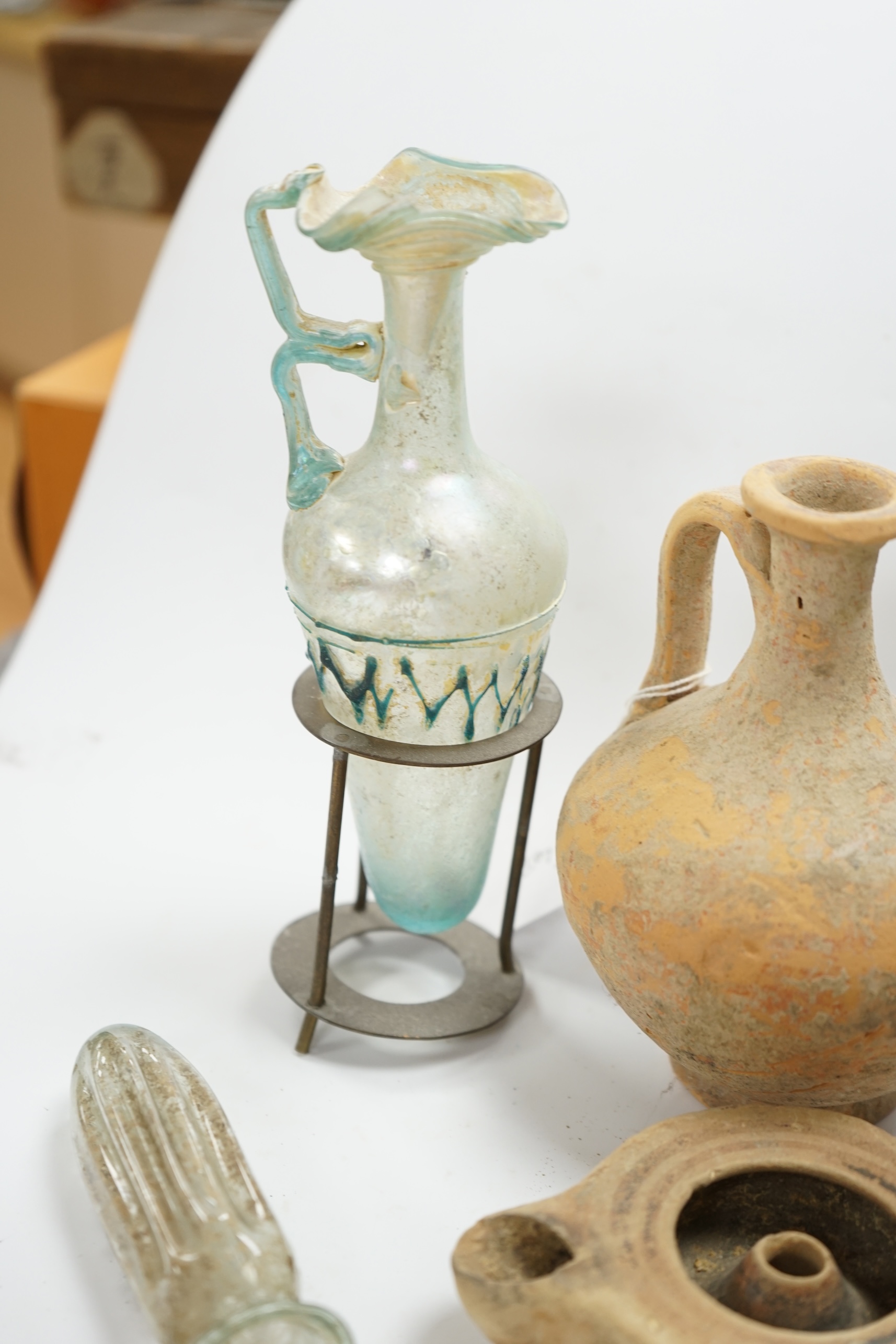 A Roman glass vase on stand, a similar Roman glass vase and three terracotta Syrian style vessels, tallest Roman vase on stand 17cm high (not including stand). Condition - Roman vase on stand cracked at neck, other vase